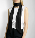 Woman wearing a black silk scarf and white blouse against a plain background