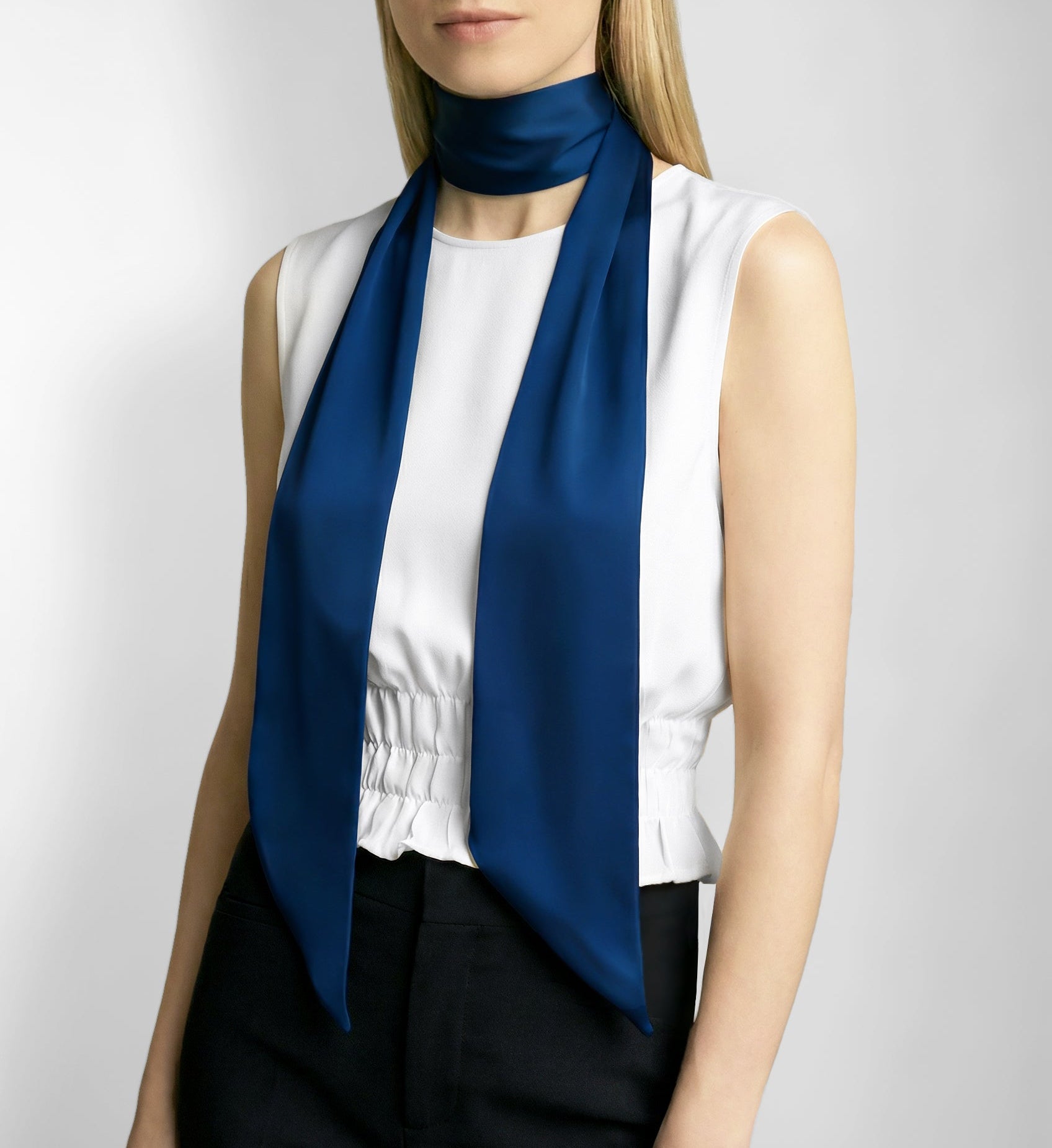 Woman wearing a blue scarf and white blouse against a plain background