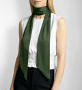 Woman wearing a green silk scarf and white blouse against a plain background