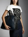 Woman holding a blue leather handbag against a gray background