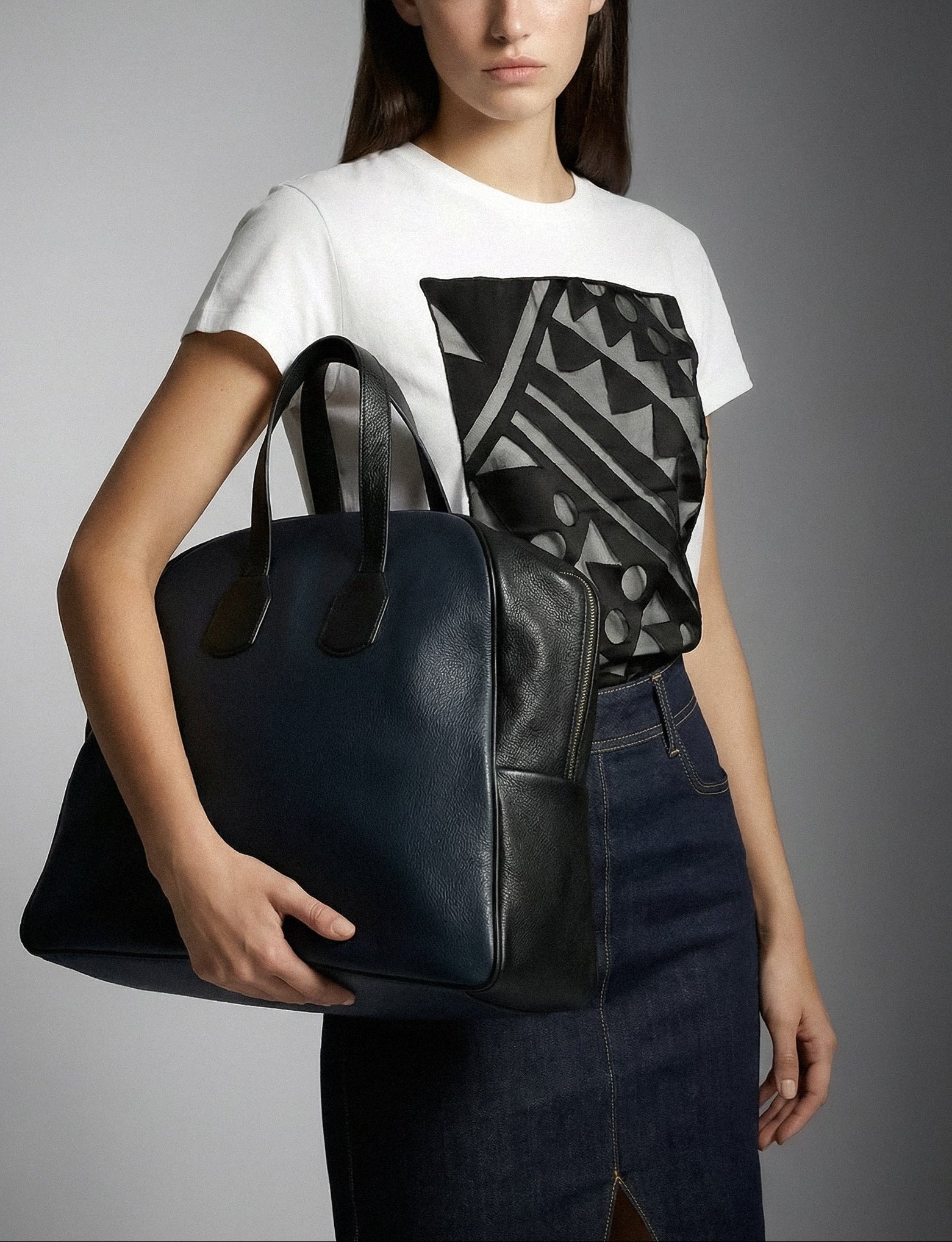 Woman holding a blue leather handbag against a gray background