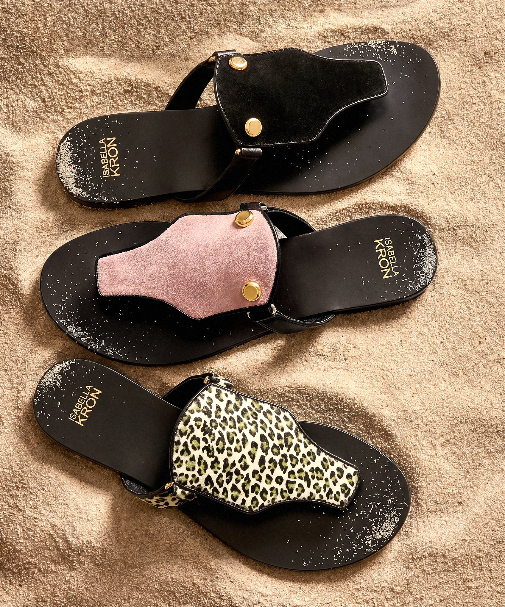 Black sandals with various embellishments on a beige surface