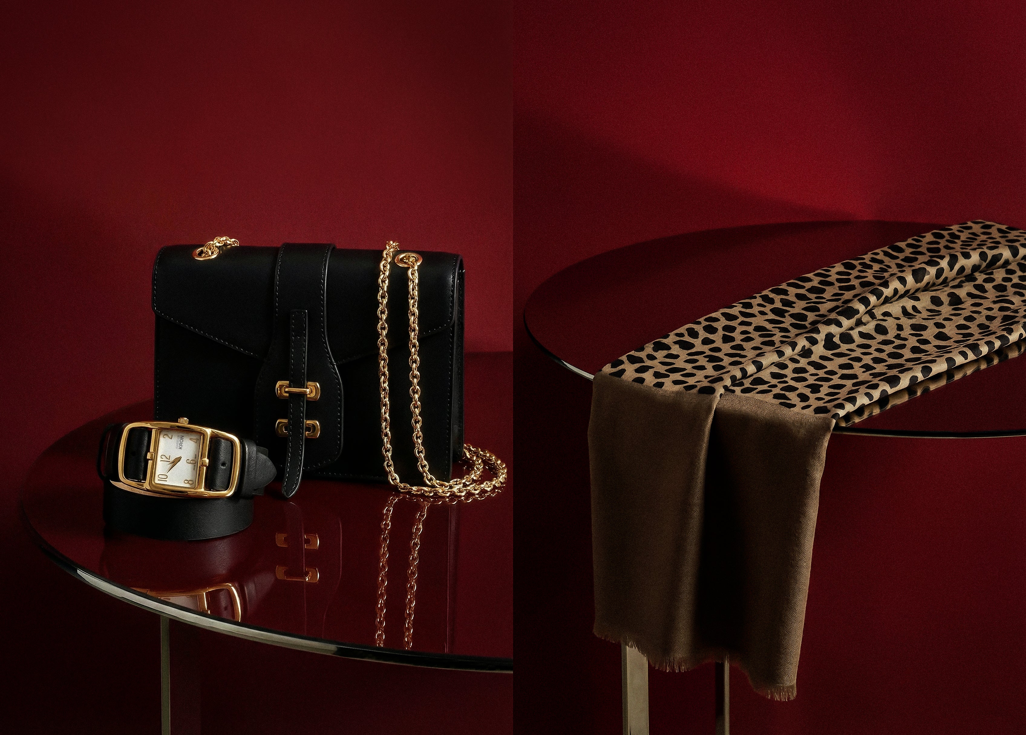 Black handbag with gold chain, belt, and leopard print blanket on a red surface.