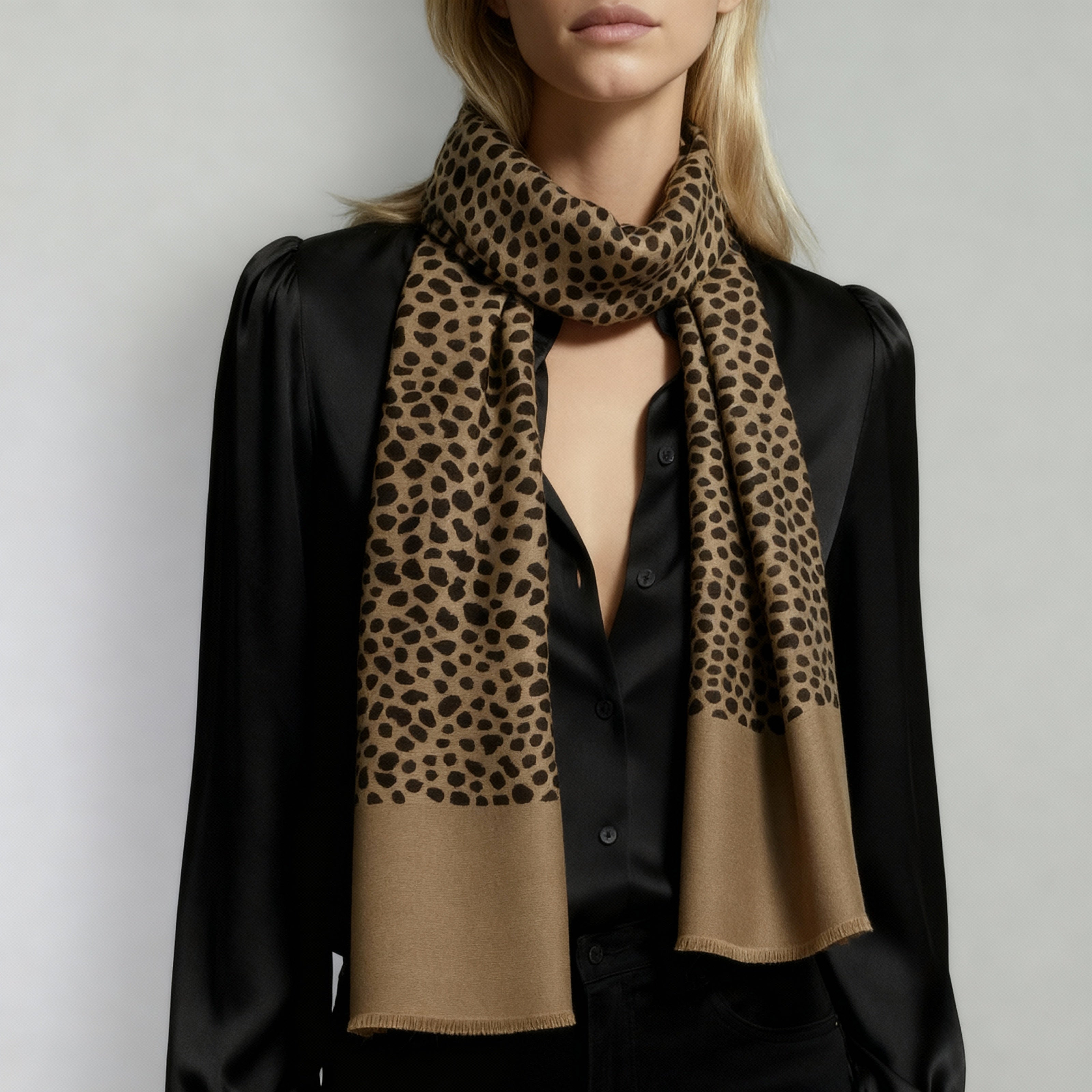 Person wearing a black shirt with a leopard print scarf on a plain background