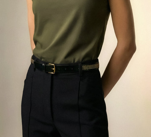 Model wearing the Isabella Kron Brea Belt in black leather studded with gold-tone hardware, featuring rectangular buckle and studs