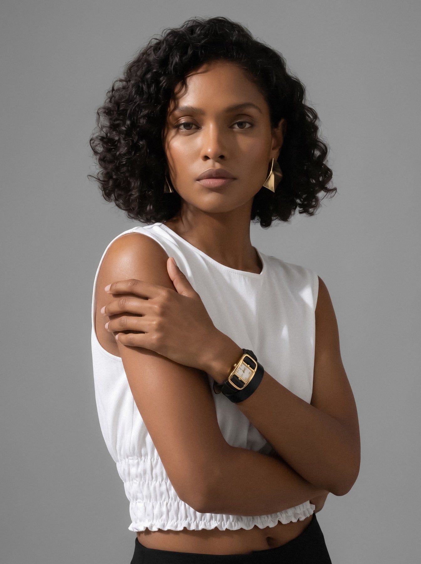 Gold watch on a female models wrist against a gray background. Gold Divaugusta Watch – sophisticated statement accessory