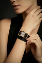 Gold watch on a wrist with a black dress against a gray background. Gold Divaugusta Watch – sophisticated statement accessory