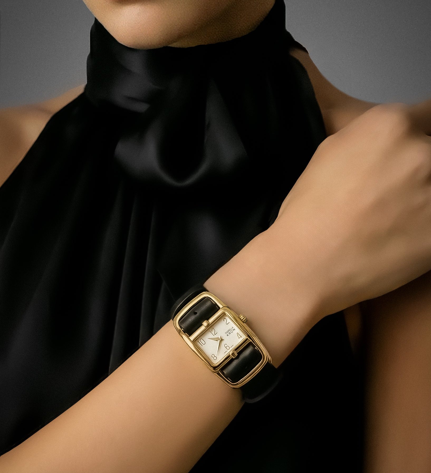Gold watch on a wrist with a black dress against a gray background. Gold Divaugusta Watch – sophisticated statement accessory