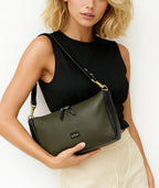 Styled view of Isabella Kron Isotta Convertible bag in military green leather, held by top handle over a neutral outfit to showcase the convertible structure