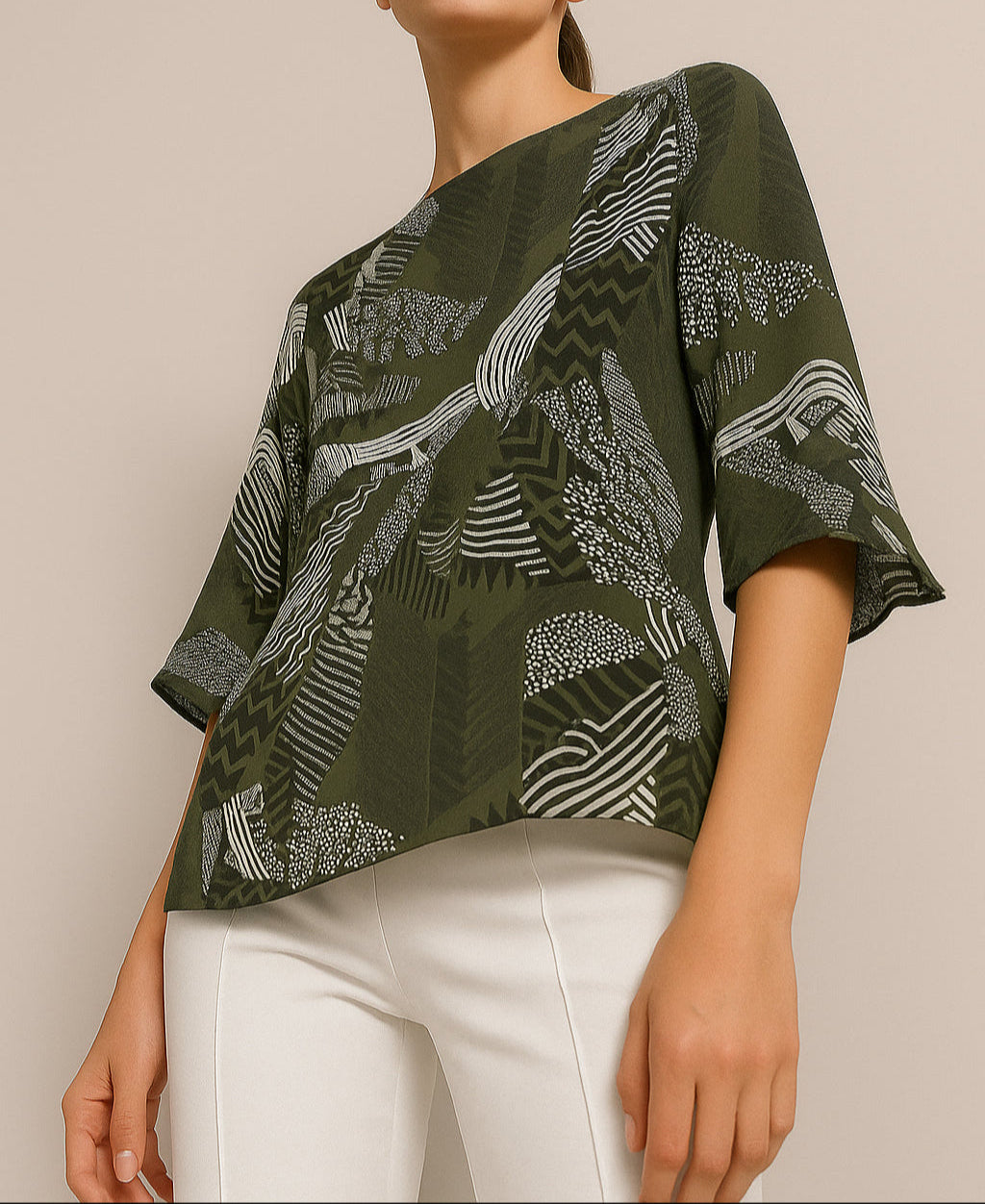 Person wearing a green patterned top with white pants on a beige background