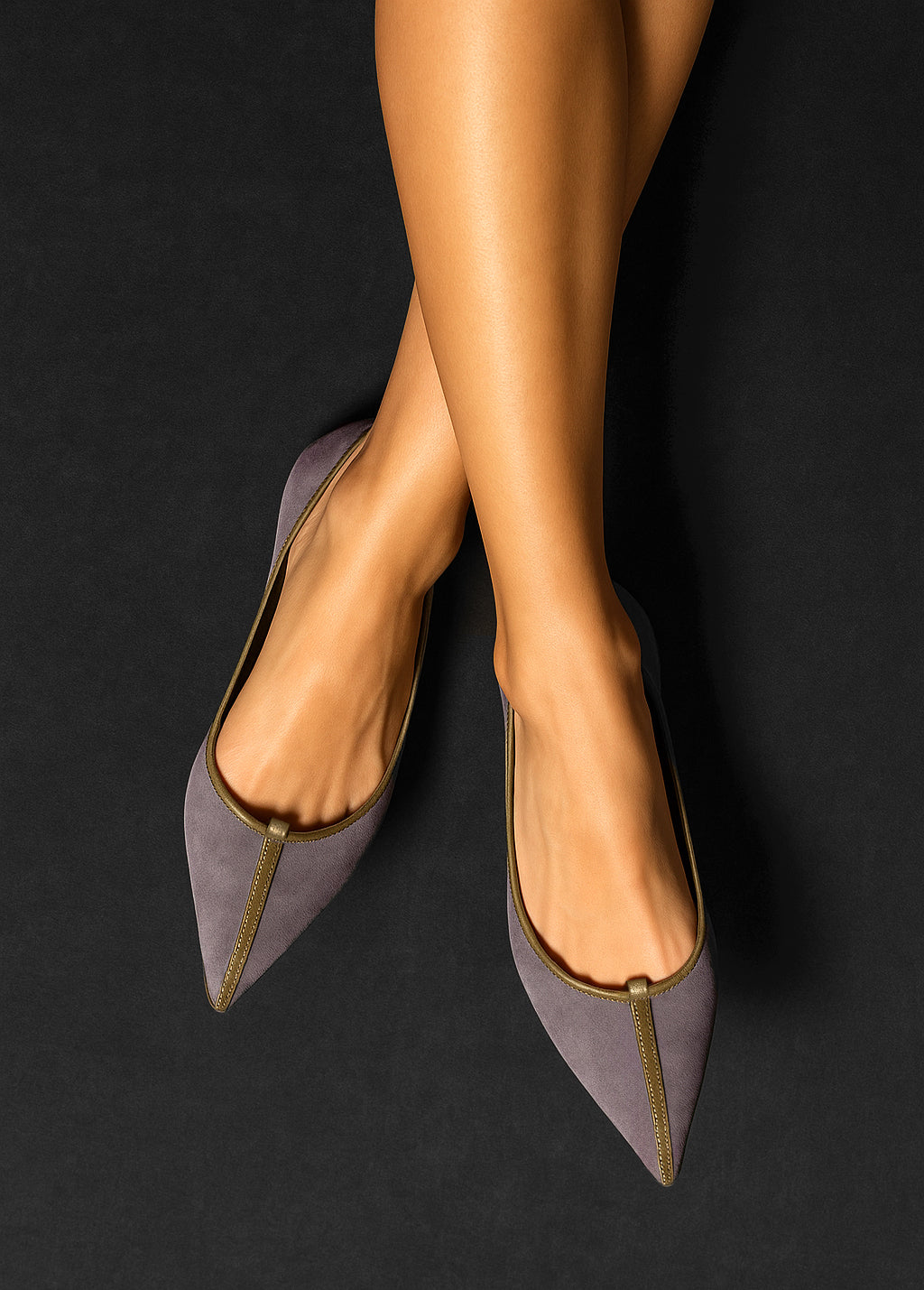 Purple high-heeled shoes worn by a person on a black background