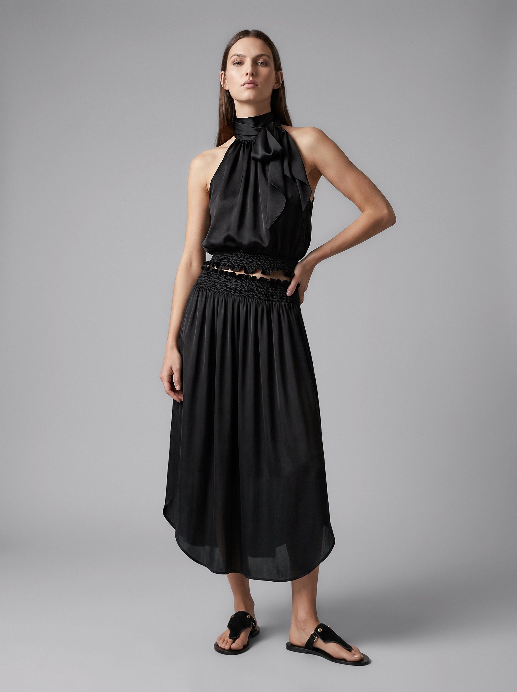 Model wearing the Lily black silk midi skirt with a smocked waistband and rounded hem