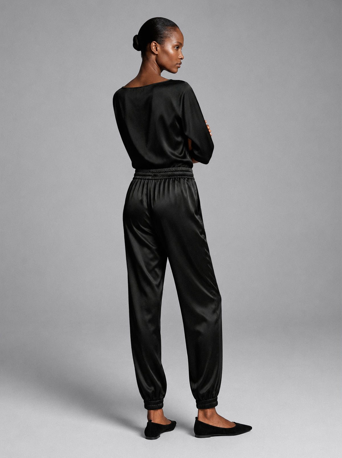 Model wearing the Lou Jogger Silk Pant in black, a relaxed-fit silk jogger, back view