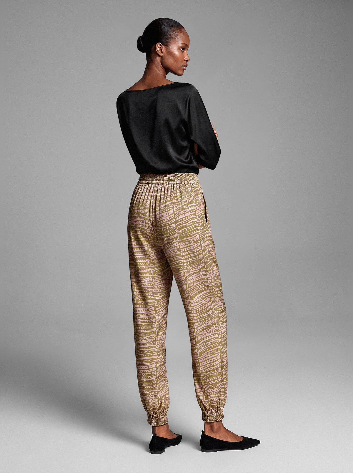 Model wearing the Lou Silk Jogger in chartreuse and pink dotty print, a relaxed-fit silk jogger with a drawstring waist and elastic cuffs, back view