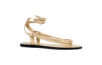 Side view of gold leather flat sandals with slender wrap straps and refined minimalist design