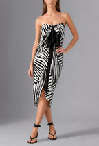 Woman wearing the Savana Pareo in white and black graphic print styled as a lightweight luxury beach wrap