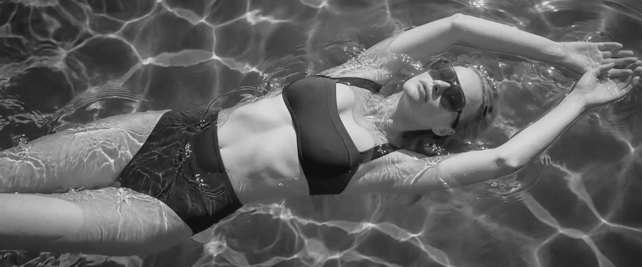 Isabella Kron female model floating in a pool with water ripples around