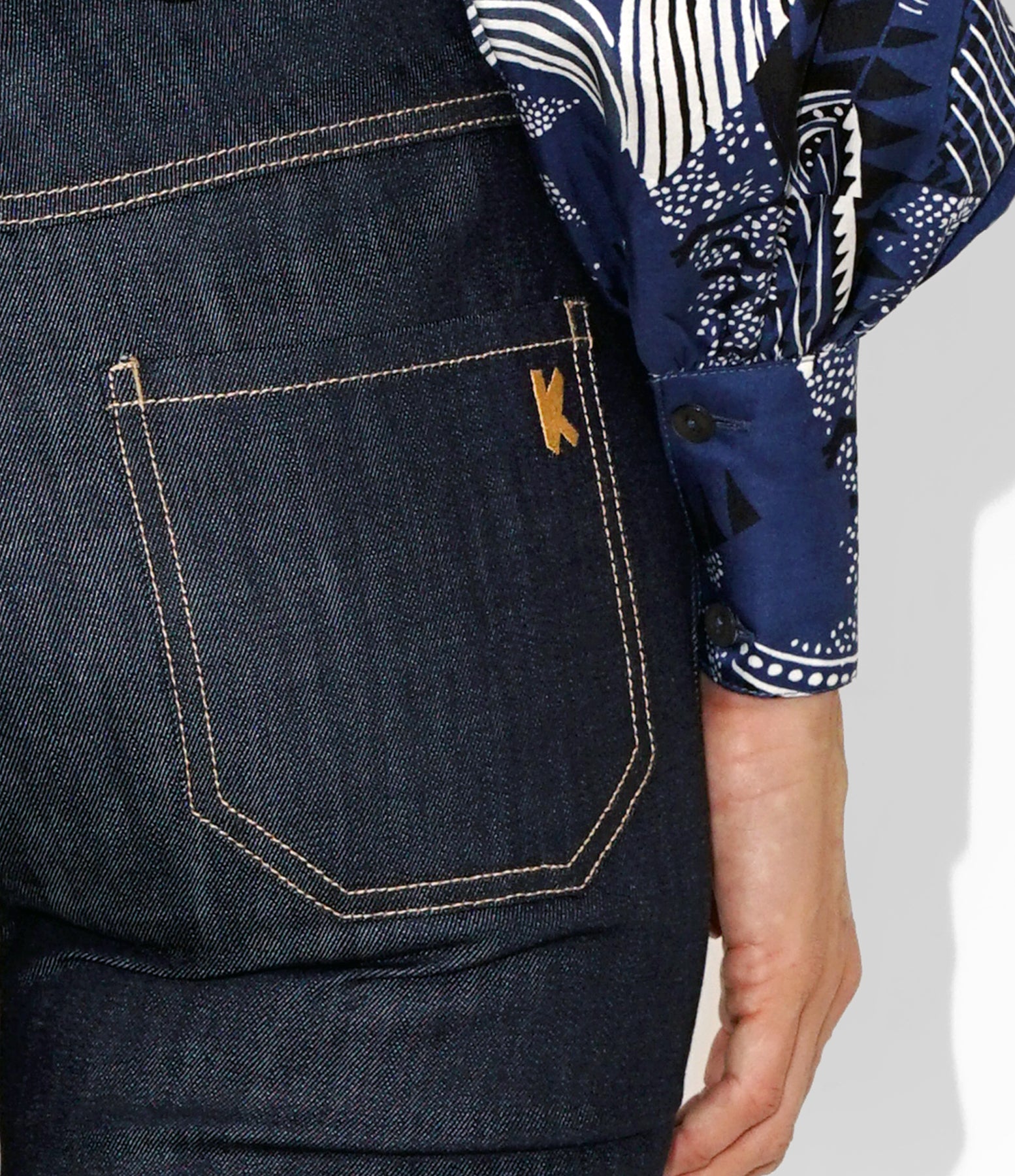 Close‑up of contrast stitching, waistband belt loops, and dark indigo stretch denim texture on Isabella Kron K‑22 Jean