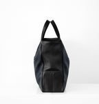 Side view of Isabella Kron Leo Shopper in blue pebbled calf leather with black trim, showing slim folded profile and dual top handles