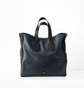 Upright front view of Isabella Kron Leo Shopper in blue pebbled leather with black contrast trim, structured silhouette with double handles and subtle branding